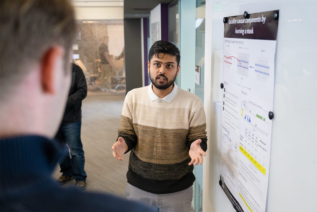 A student explains his poster presentation to an audience