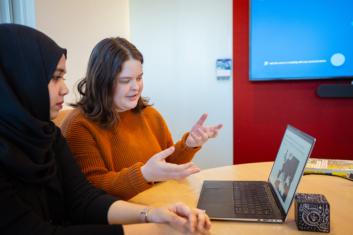 Two students read a slideshow off a laptop