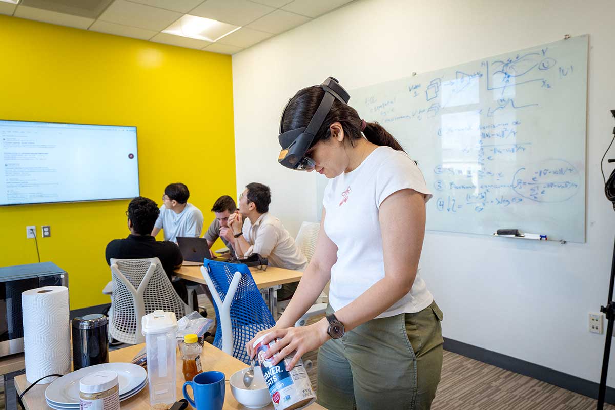 A student wearing smart glasses pours oatmeal into a bowl