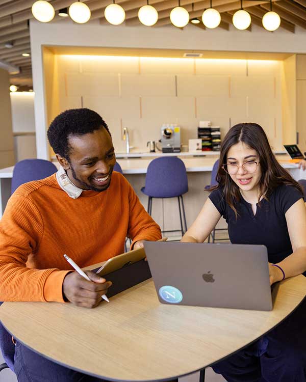 Two Khoury students look at a laptop while working together on a project