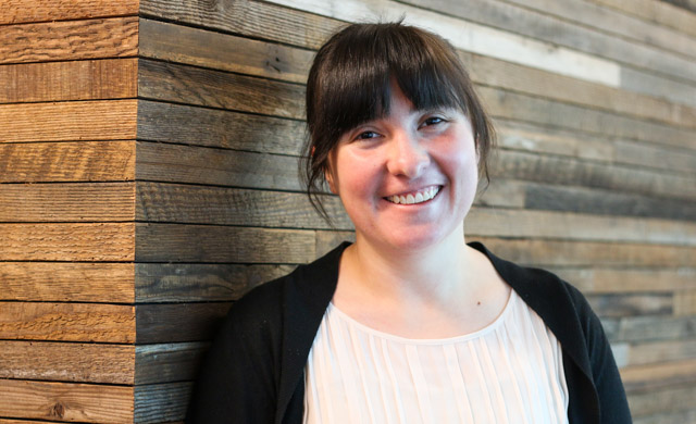 Tamara Bonaci stands and smiles leaning against a wooden wall at Northeastern Seattle.