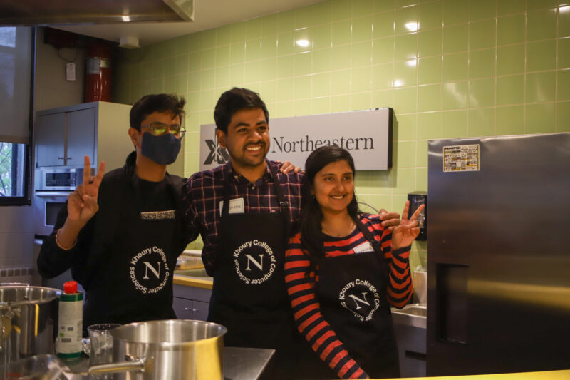 one woman and two men with their arms around each other in a kitchen