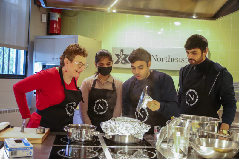 dean watching as three students cook in a kitchen