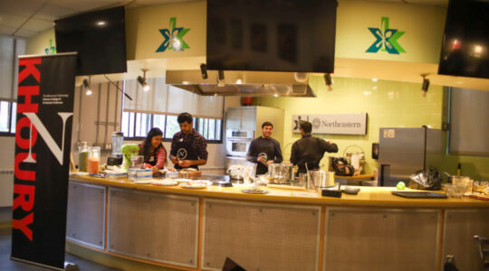 Four students cook a meal behind a counter in Xibition Kitchen
