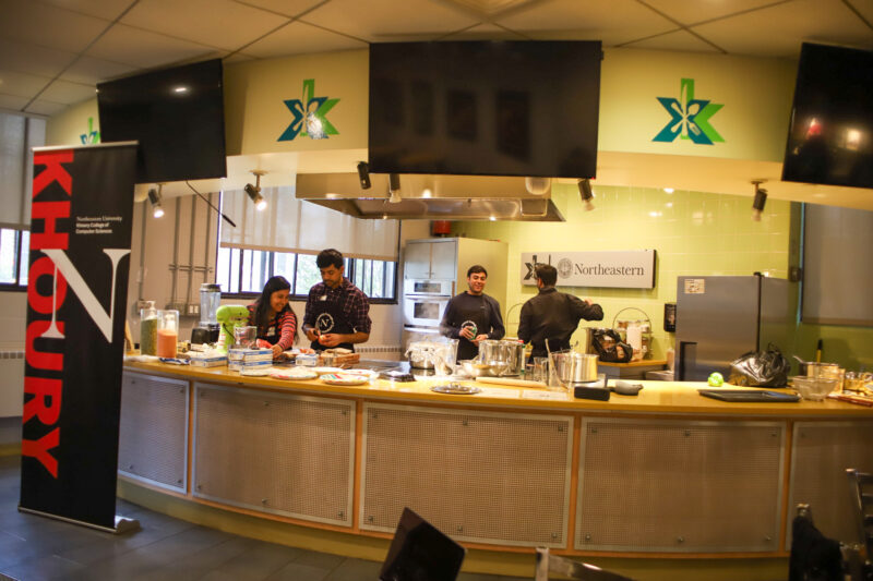 Four students cook a meal behind a counter in Xibition Kitchen