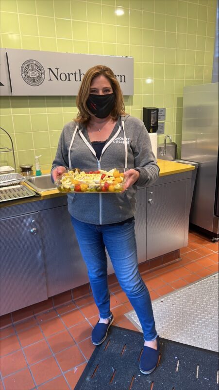 woman holding a dish of vegetables in a kitchen