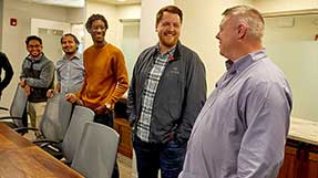 Five people talk around a conference table. Image of SimpliSafe engineers and staff provided by the company.