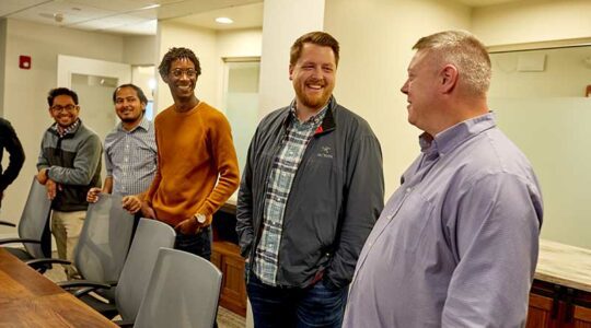 Five people talk around a conference table. Image of SimpliSafe engineers and staff provided by the company.