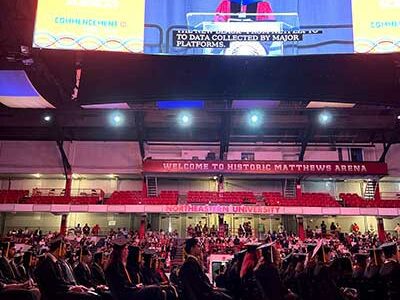 Khoury College graduates watch Dean Elizabeth Mynatt deliver a speech at the 2022 Khoury celebration