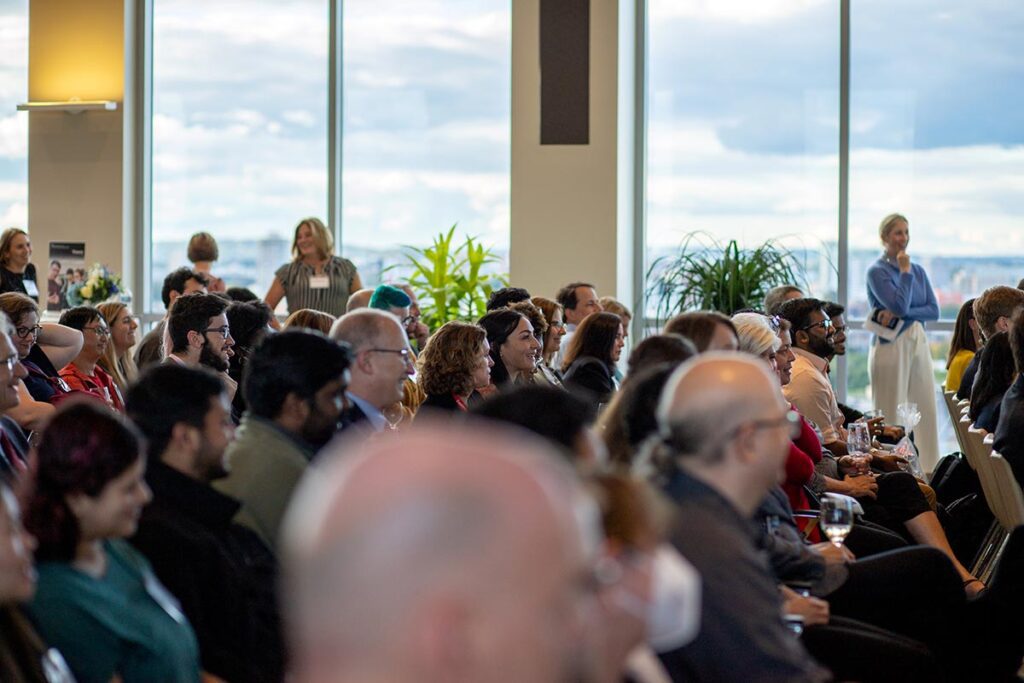 Students, faculty, staff, alumni and business partners listen to speaking portion of program