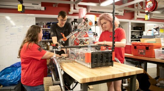 From left to right: Shannon McInnis, Garrit Strenge, and Brooke Chalmers work on the rover. Photo by Sarah Olender.