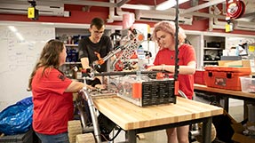 From left to right: Shannon McInnis, Garrit Strenge, and Brooke Chalmers work on the rover. Photo by Sarah Olender.