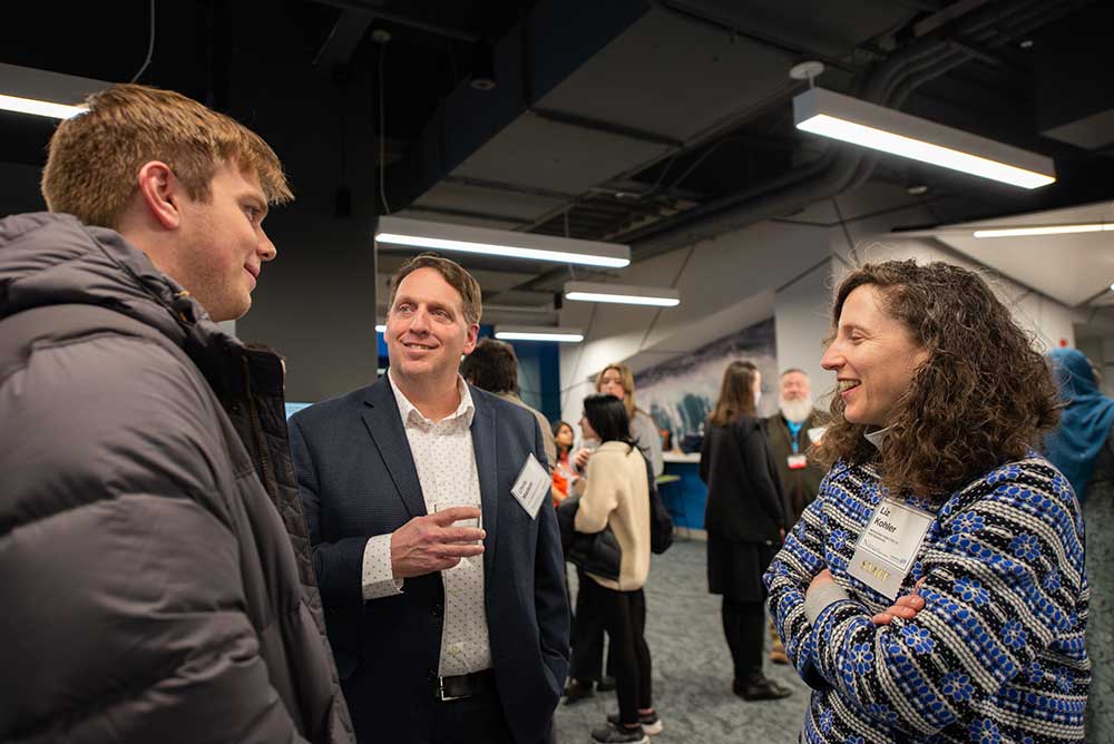 Chris Mallett, Chief Administrative Officer at the Roux Institute and Liz Kohler, Managing Director of Partnerships at the Roux Institute socialize with a student at the 40th Anniversary Celebration.