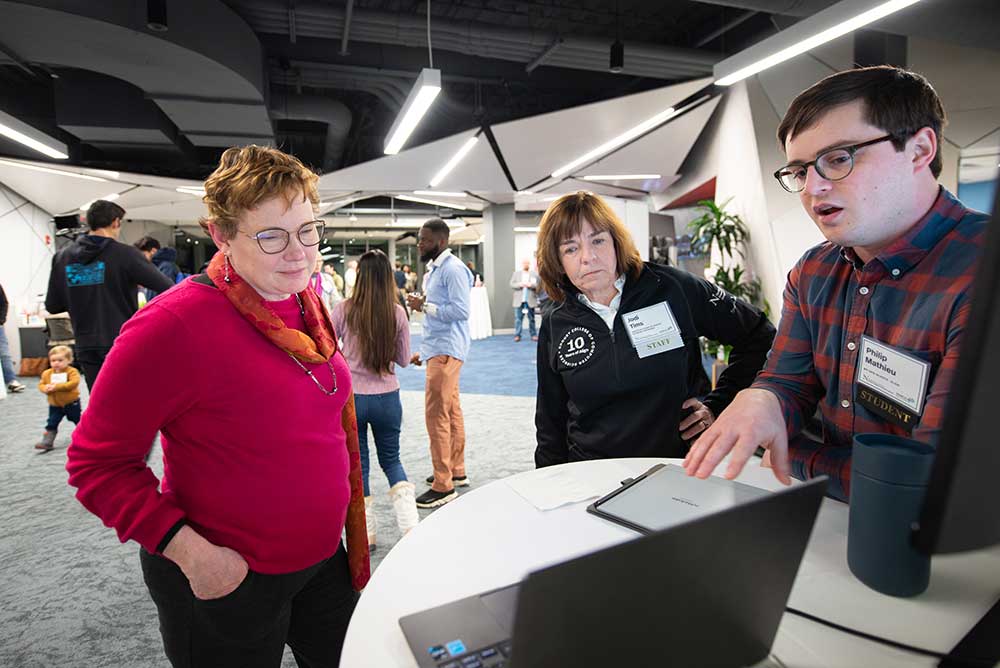 Student Philip Mathieu from the Roux Institute, presents to Dean Elizabeth Mynatt and Jodi Tims, Associate Dean of Khoury Network Programs, at the 40th Anniversary Celebration.