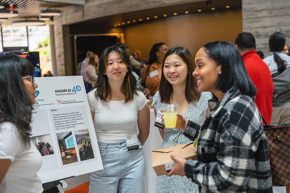 A student explains a research project while standing in front of a poster