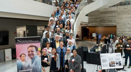 Khoury College faculty gather on the large staircase in the Interdisciplinary Science and Engineering Complex