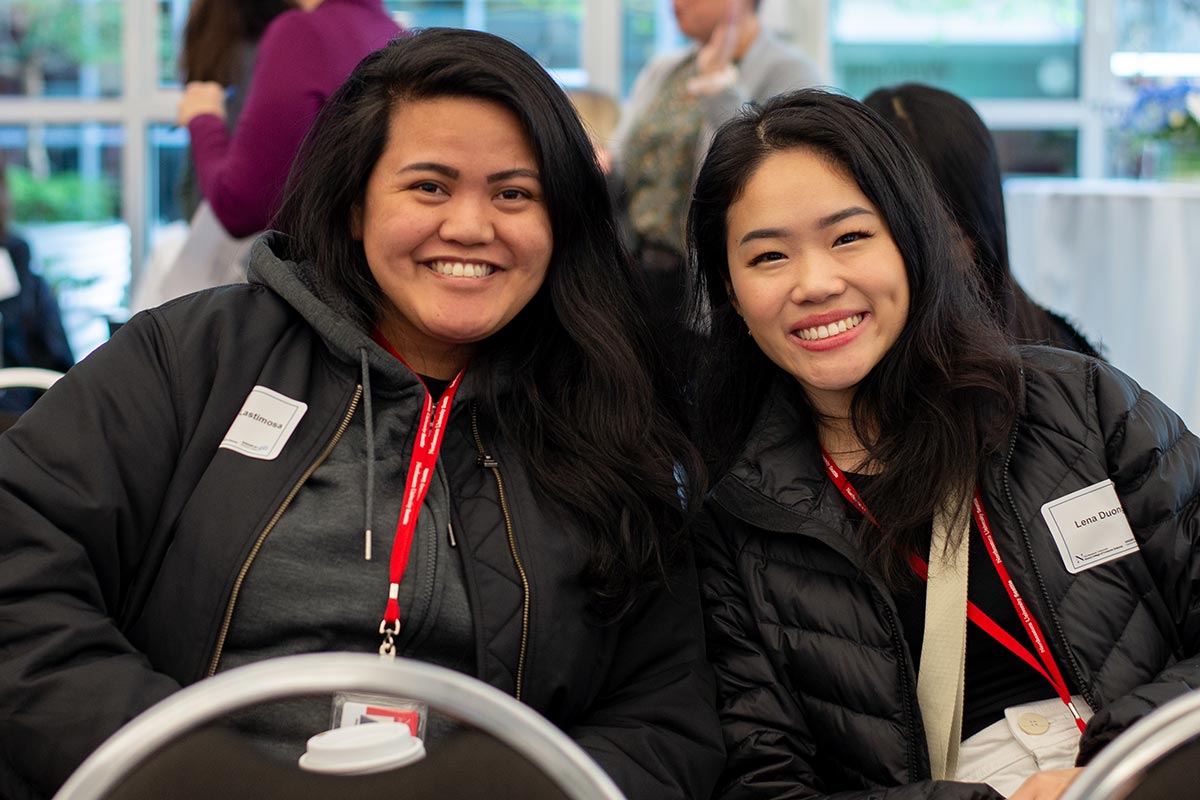 Two audience members smile at the Khoury 40th anniversary celebration in Seattle.