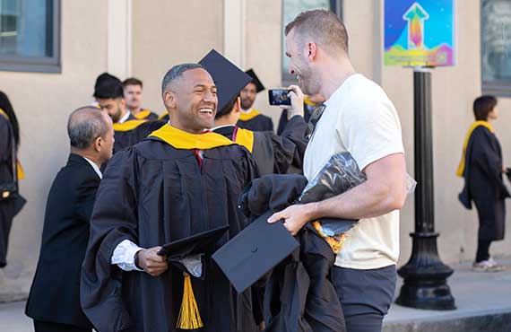 Two ceremony participants laugh outside Matthews Arena