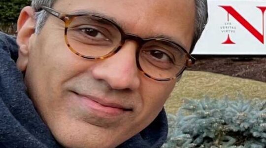 Mani Sundaram stands in front of a Northeastern sign