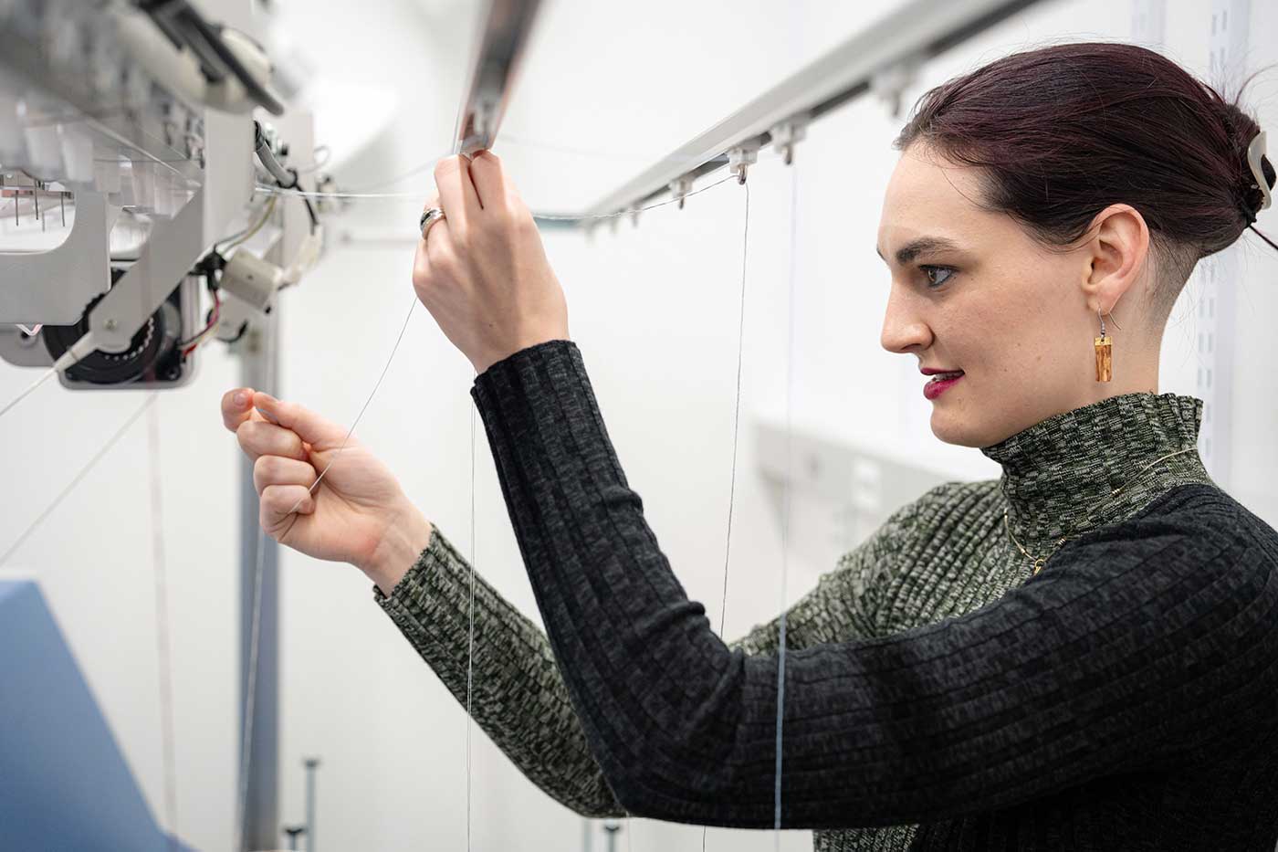 Megan Hoffman works with a knitting machine.