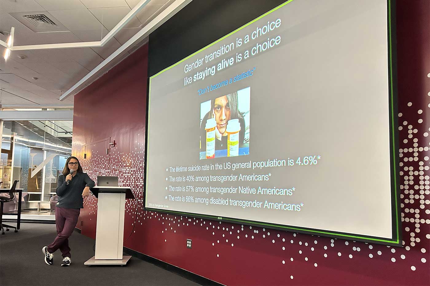 Kylie Bemis stands at a podium while giving a presentation in front of a screen showing her slides