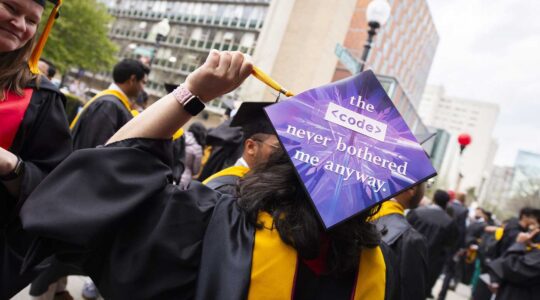 A graduate shows the back of a graduation cap with a sign that says 'the code never bothered me anyway'