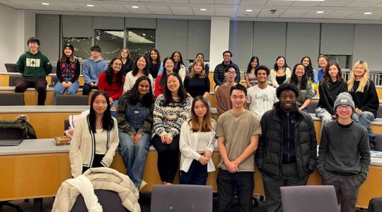 About 30 members of code4community pose for a photo taken in a Northeastern classroom during a club meeting.