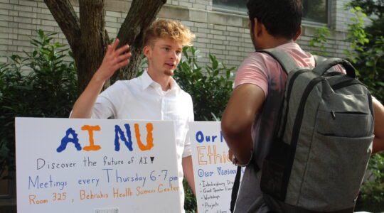 A student standing behind a poster that says "AI at NU" talks about the Artificial Intelligence club with another student