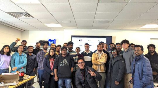 25 members of the Google Developer Student club pose for a photo in a Northeastern classroom. A presentation screen is visible in the background.