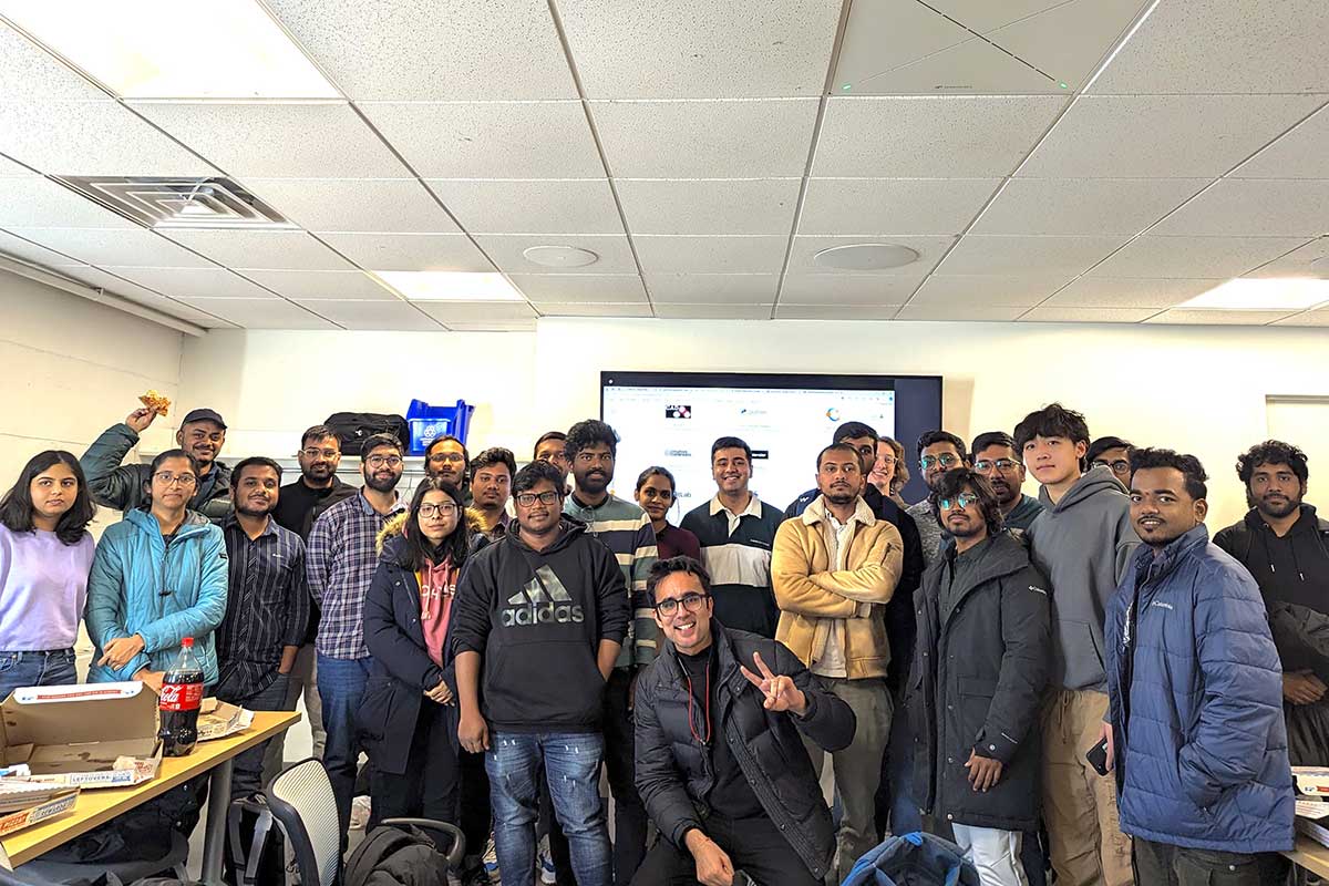 25 members of the Google Developer Student club pose for a photo in a Northeastern classroom. A presentation screen is visible in the background.