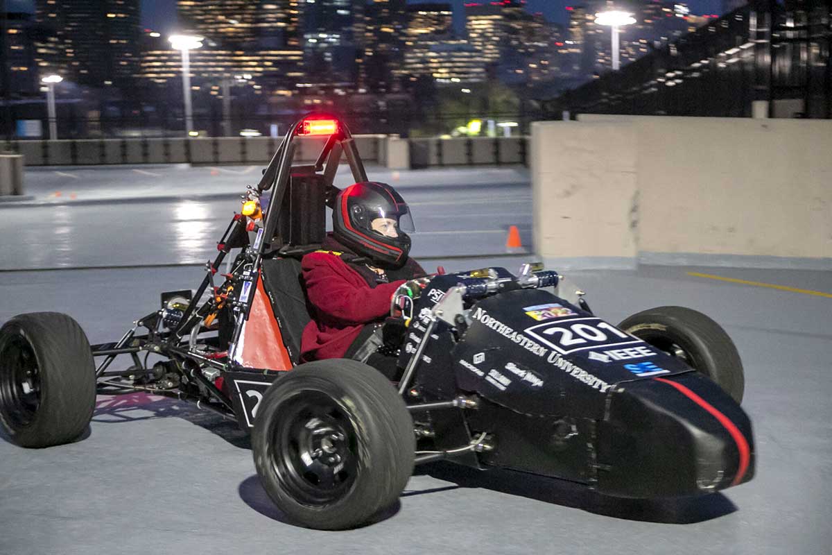 Dean Elizabeth Mynatt drives Northeastern Electric Racing's car in a Northeastern parking lot.