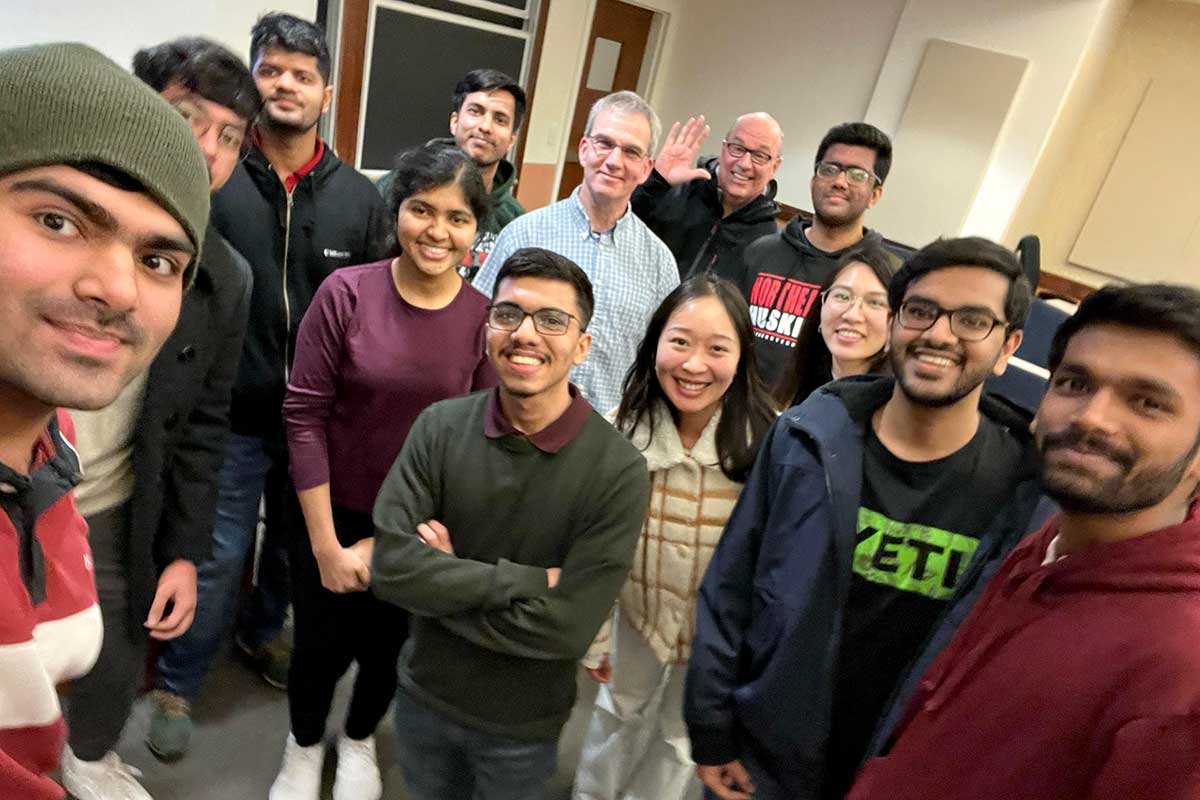 Thirteen members of the null NEU club smile while they pose for a selfie.