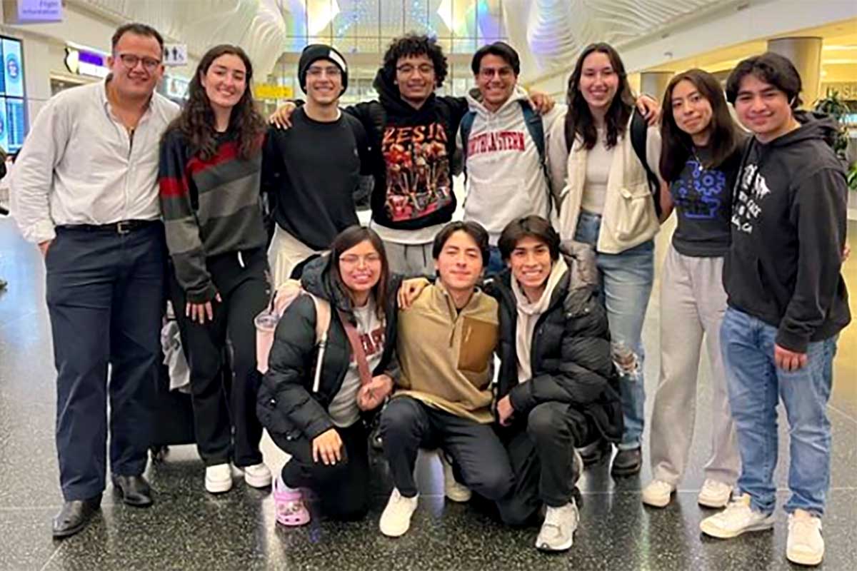 Eleven members of the Society for Hispanic Professional Engineers pose for a photo in a conference center. The first row shows three students kneeling and the other eight students are standing in the back row.