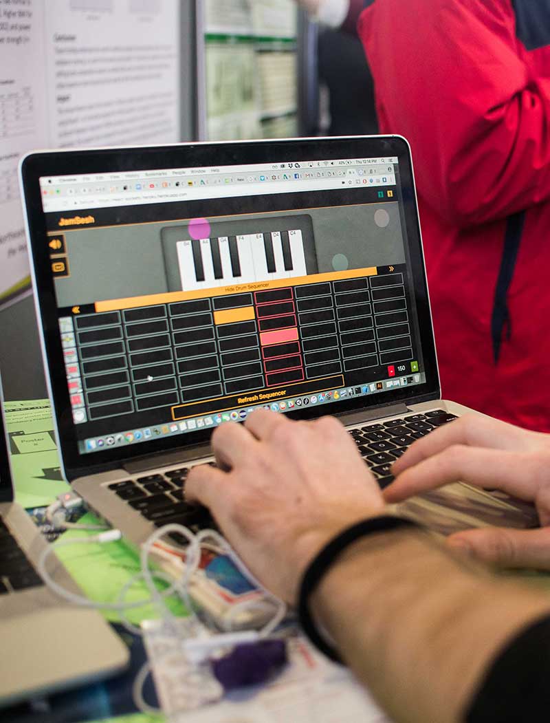 A close-up view of a laptop screen that shows a person's hands typing on the laptop's keys. The laptop screen shows what appears to be piano keys.