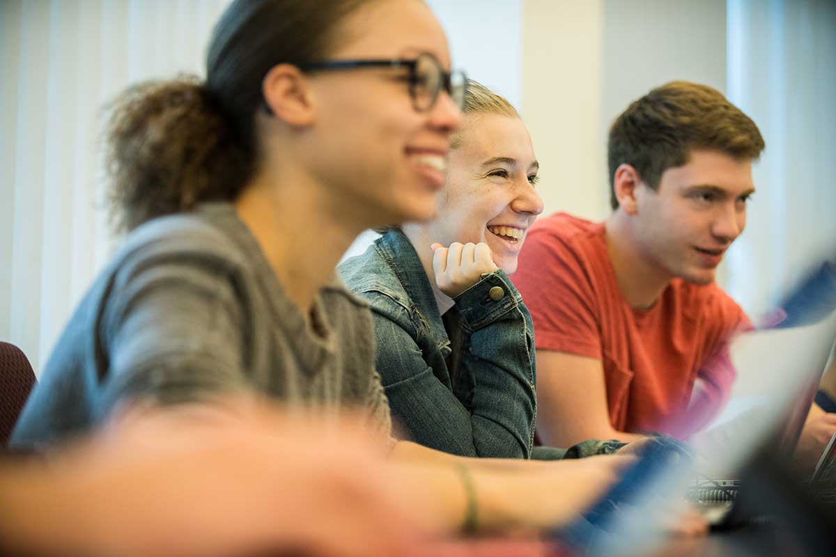 Three students smile during a class presentation.