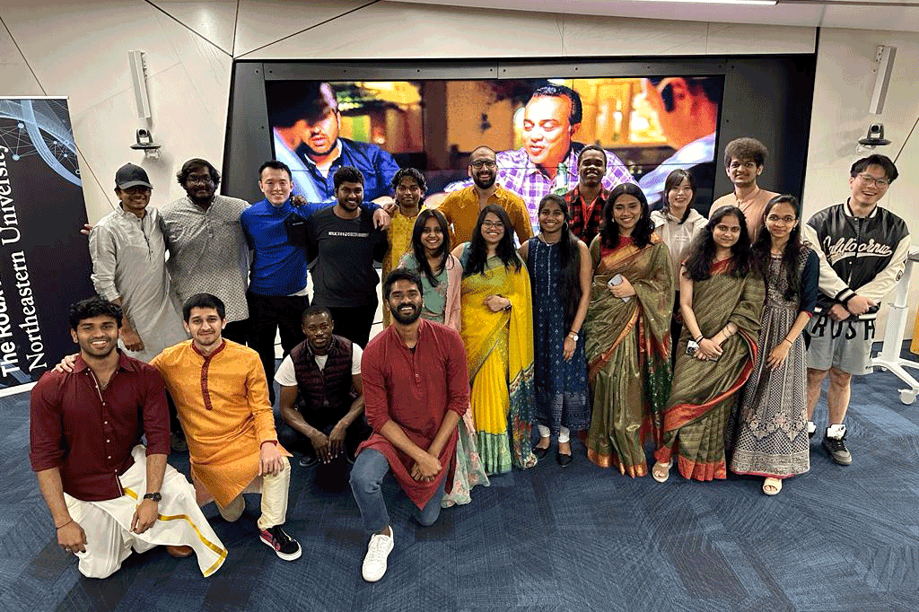 Twenty members of Namaste pose for a photo a the club's Diwali celebration. Four members are resting on one knee in the front row. The rest of the club members are standing behind them.