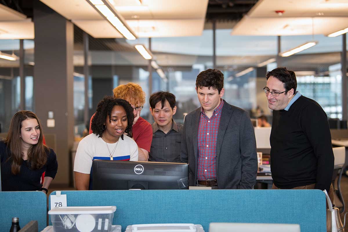 Khoury faculty members Daniel Wichs, right, and Jonathan Ullman, second from right, look at a computer screen that four other researchers are viewing.