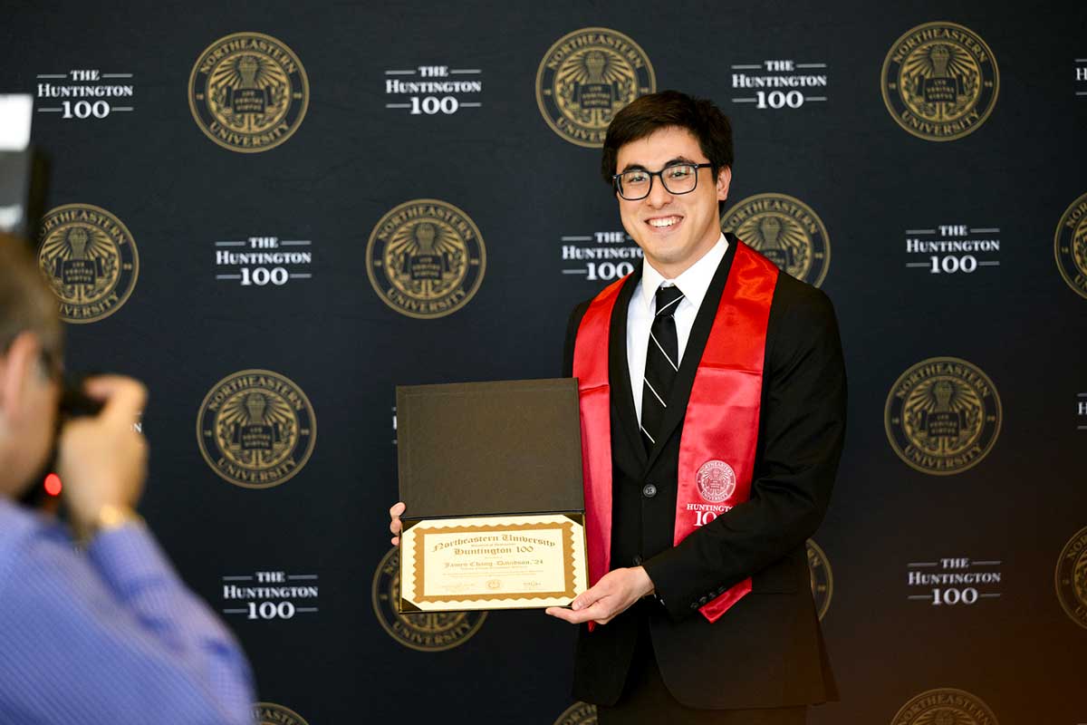 A Khoury College graduate poses with a Huntington 100 certificate