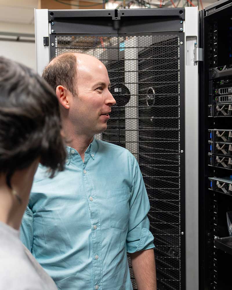 Khoury faculty member Jonathan Bell, right, looks at an open rack of servers.