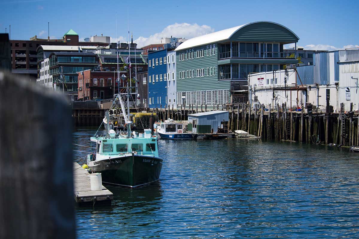 A view of a port in Portland, Maine with three boats docked at a pier.