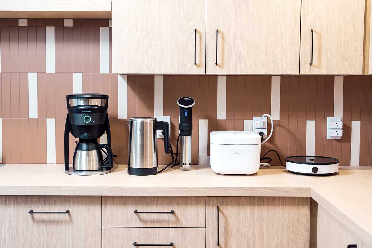 Five smart devices sits on a kitchen counter in the Wireless Internet of Things lab. The devices are a coffee maker, electric water pitcher, an espresso machine, an electric break maker, and an electric hot plate.