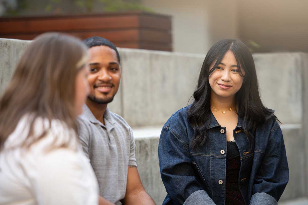 A group of students converse while sitting on benches in the courtyard of Northeastern's Silicon Valley campus