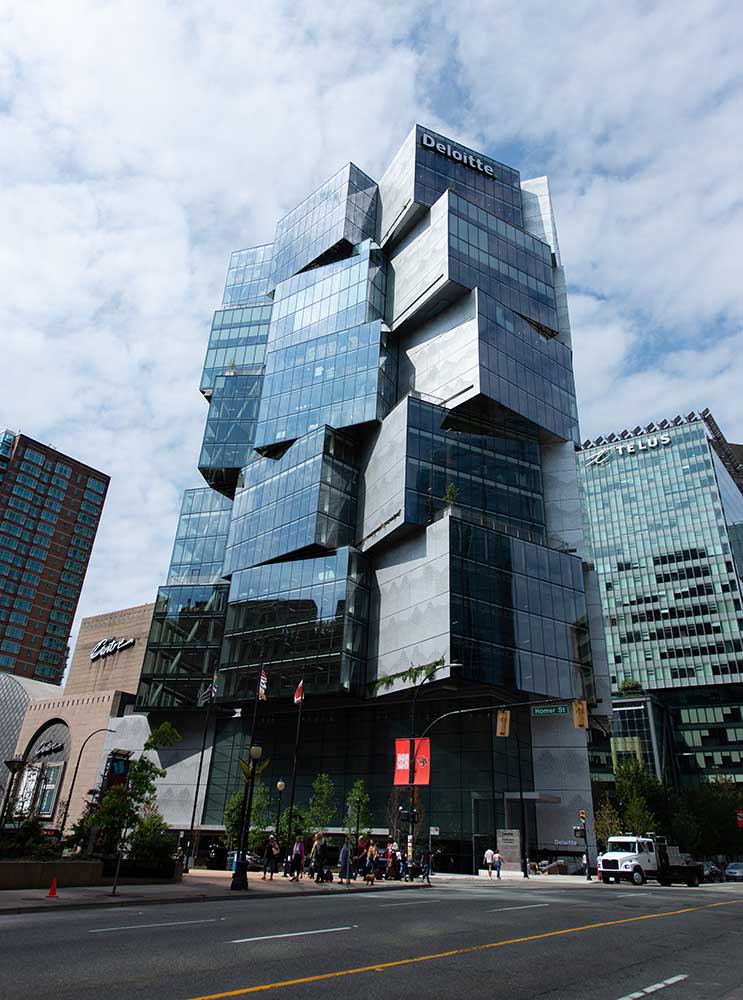 A photo of the Northeastern Vancouver building. The buliding's glass exterior looks like building blocks unevenly stacked on top of each other.