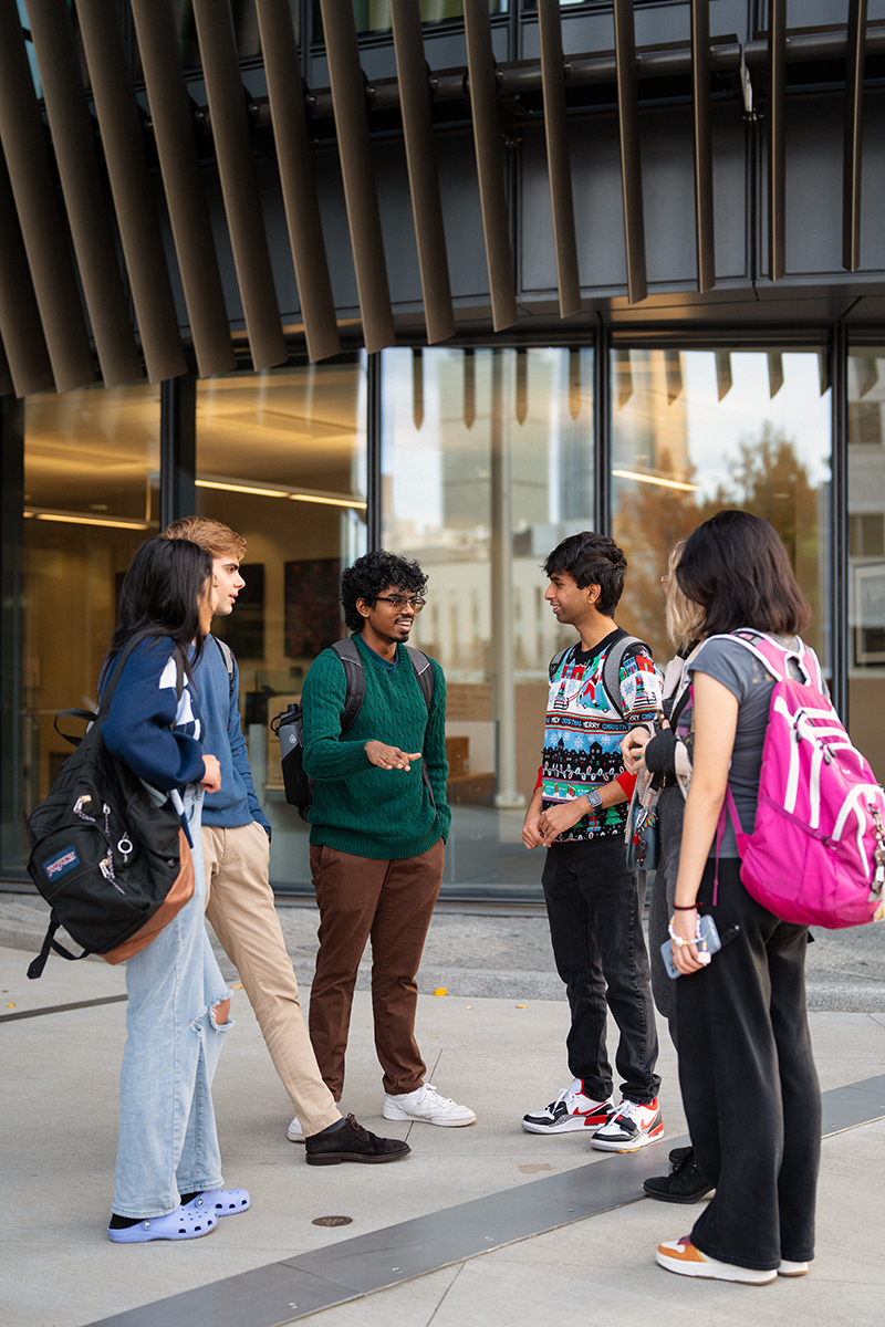 Six students have a conversation in front of a Northeastern building