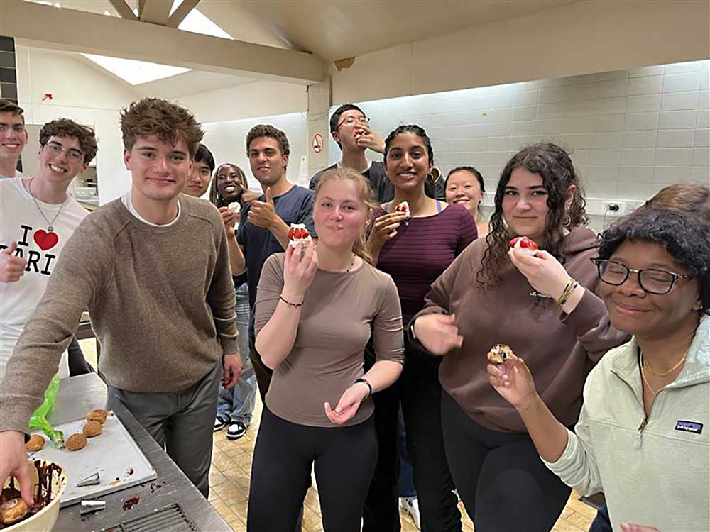 A group of 12 students taste slices of a strawberry cake