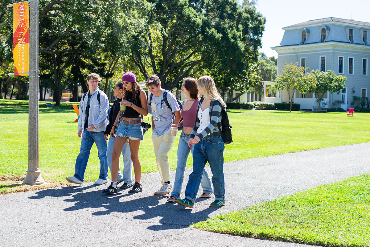 Six students walk along a gravel walkway on the Mills College campus in Oakland