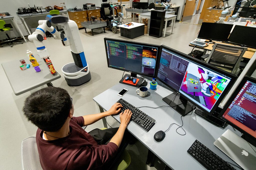 A student works at a computer in a robotics lab