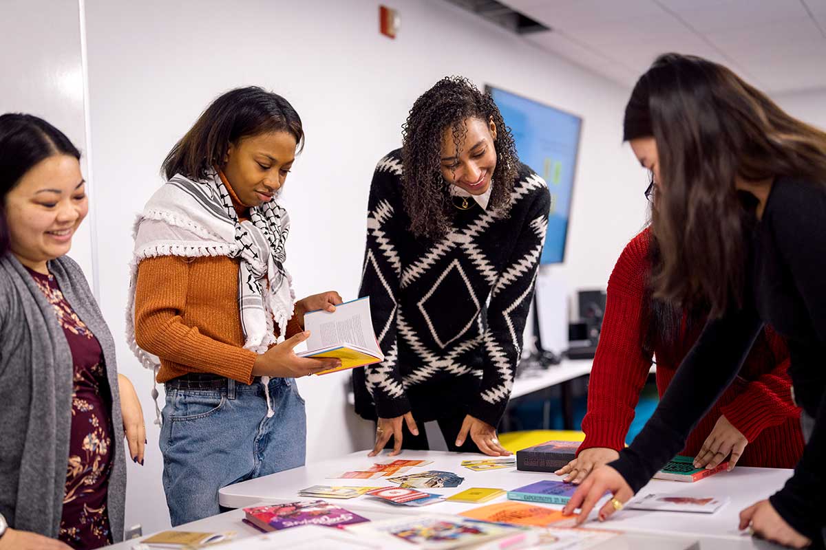 Five researchers stand around a table and look at books related to games research.