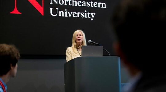 A member of Northeastern's administration speaks behind a black podium