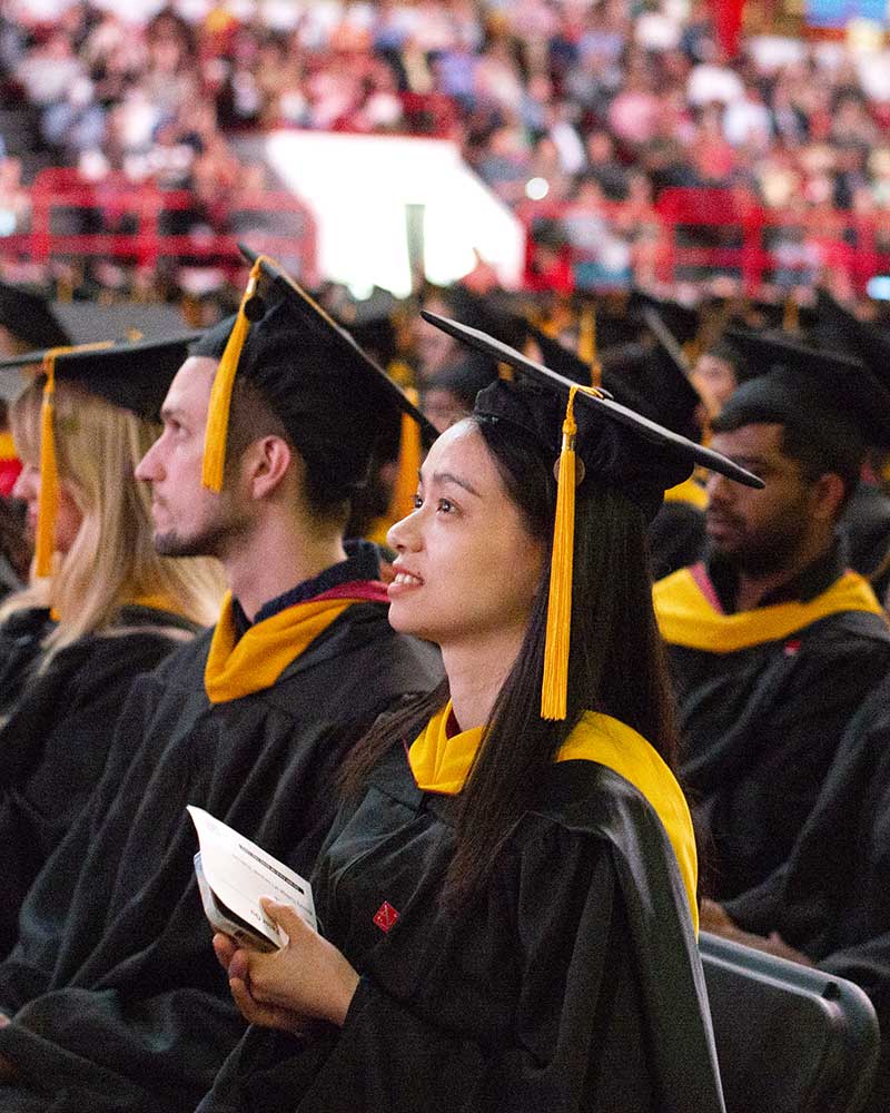 Students sitting in chairs view the stage at the 2024 Khoury graduation celebration